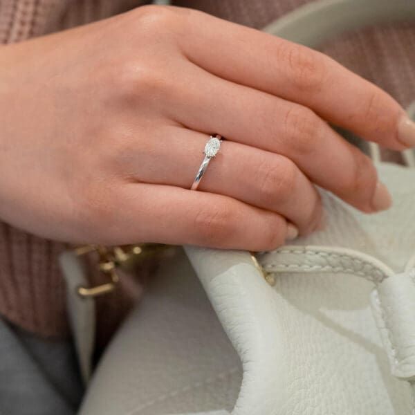 Model Wears Jolie Oval 6X4 Diamond 4 Prong East West Set Solitaire Rounded Band White Gold Ring