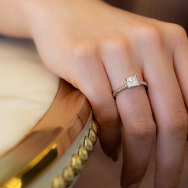 Model Wears Leisel Square 5.5 Front Moissanite 4 Prong Crossover Gallery Solitaire Band White Gold Ring