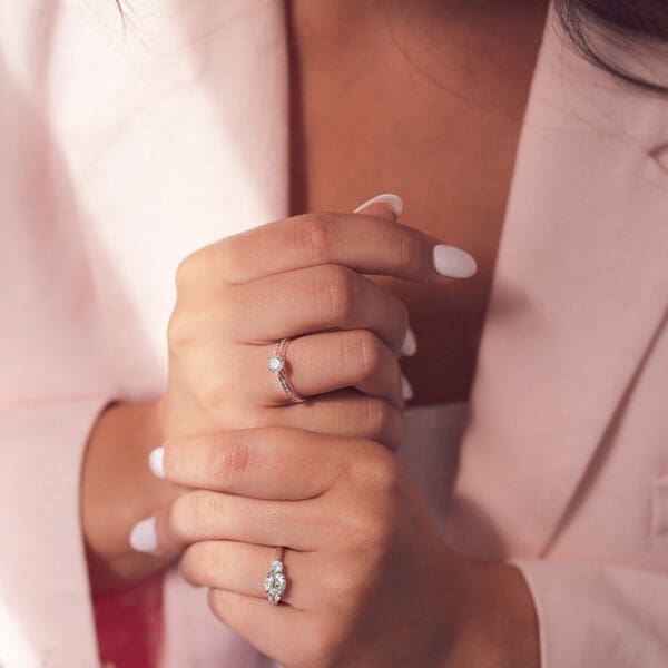 Model Wears Theresa 6.5 White Gold Diamond 4 Prong Trilogy Heart Knife Edge Ring And Bailey 6.0 Double Prong Round Channel Set Ring