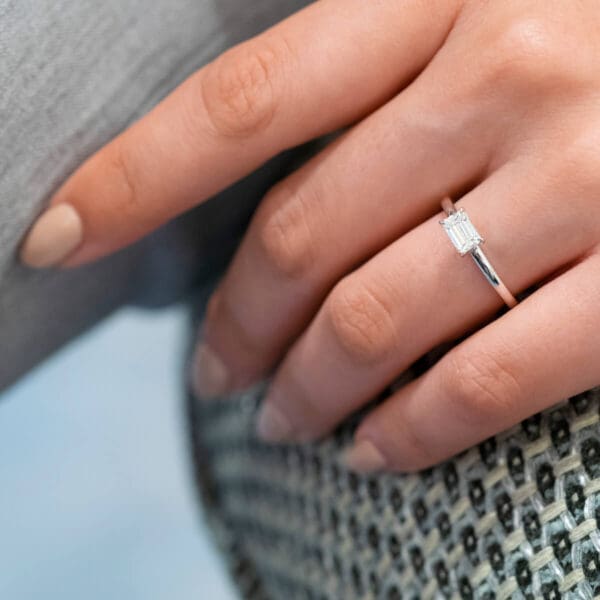 Model Wears Jolie Emerald 6X4 Diamond 4 Prong East West Set Solitaire Half Rounded Band White Gold Ring