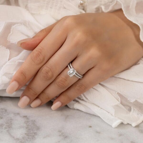 Model Wears Rosewood A White Gold Moissanite Straight Prong Set Wedding Band Rosewood Emerald 9X7 Open Basket Ring