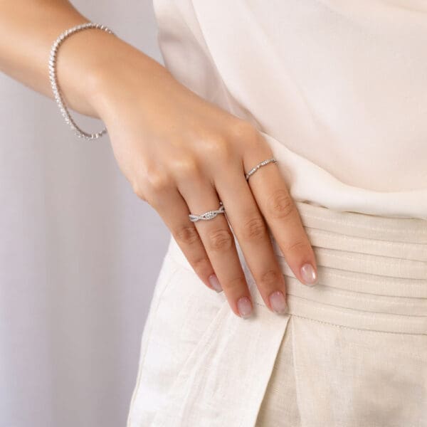 Model Wears Rylie White Gold Diamond Channel Crossover Infinity Wedding Band Sadie Round Tapered Sections Pave Set Ring