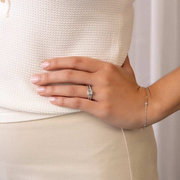 Model Wears Holly Emerald 7X5 White Gold Diamond Four Prong Solitaire Ring Millie 1 3 Moissanite Pave Set Wedding Band