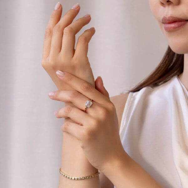 Model Wears Iliana 9X7 Yellow Gold Moissanite East West Emerald Semi Rounded Band Solitaire Ring