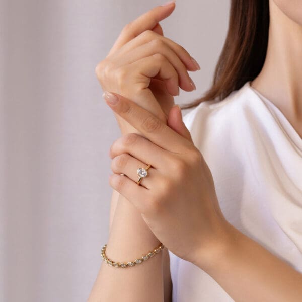Model Wears Lottie Oval 8X6 Yellow Gold Moissanite Bezel Rounded Band Solitaire Ring Petra Diamond Oval Tennis Bracelet