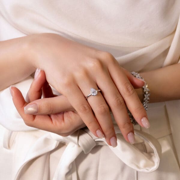 Model Wears Lottie Pear 9X6 White Gold Moissanite Bezel Rounded Band Solitaire Ring