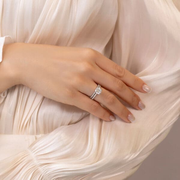 Model Wears Harmony Cushion 7 5 White Gold Moissanite Encrusted Under Rail Bridge Ring Angelica 1 5 U Prong Set Wedding Ring