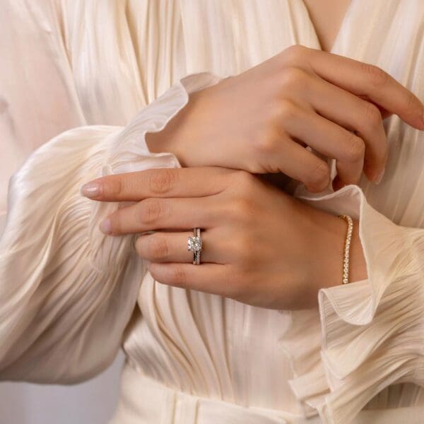 Model Wears Primrose Cushion 7 5 White Gold Moissanite Petal Basket Underrail Accented Bridge Edith 1 5 V Dip Centre Ring