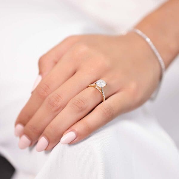 Model Wears Harmony Oval 9X7 Yellow Gold Moissanite 4 Prong Accented Under Rail Bridge Engagement Ring